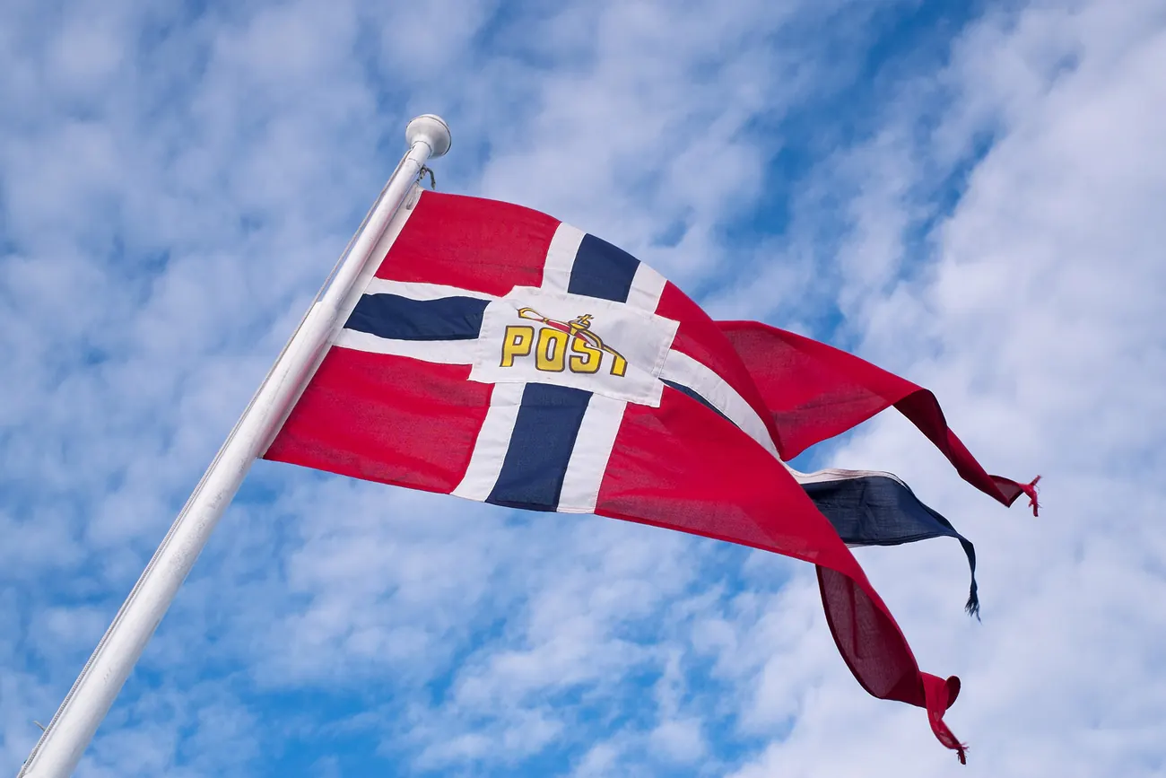 Drapeau postal norvégien claquant au vent au-dessus du port de Skutvik